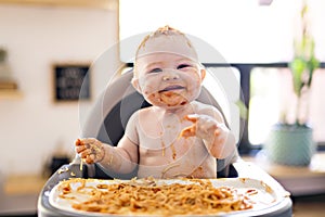 Little baby girl eating her spaghetti dinner and making a mess photo