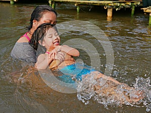 Little baby girl enjoys playing water in a river with her auntie