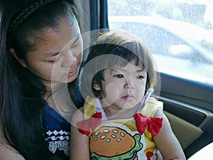 Little baby girl feeling sad, upset, depressed in a car with the mother being by her side - providing a child an emotional support