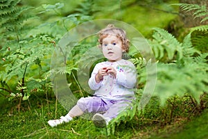 Little baby girl gathering wild raspberries in park