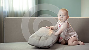 Little baby girl having fun on sofa, discovering world, posing for camera