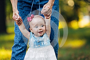 Little baby girl and her mother walking in the park. Blue eyes. Smiling.