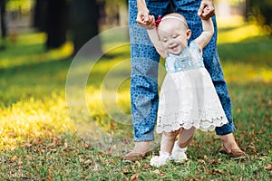 Little baby girl and her mother walking in the park. Blue eyes. Smiling.