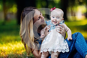 Little baby girl and her mother walking in the park. Blue eyes. Smiling. Teeth