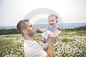 Little baby girl and his father enjoying outdoors in field of daisy flowers