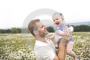 Little baby girl and his father enjoying outdoors in field of daisy flowers