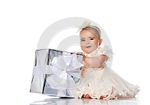 Little baby girl holding a big gift box in her hands on a white background.