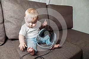 Little baby girl holding in hands big headphones