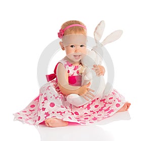 Little baby girl hugging a toy bunny rabbit on white