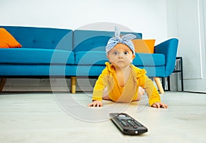 Little baby girl lay on the floor with tv control