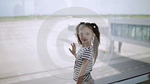 Little baby girl looks out of window at airport.