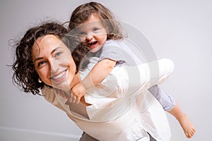 Little baby girl and mommy playing at home sitting on floor, mother and daughter laughing having fun together