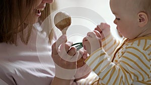 Little baby girl and mommy playing wooden eco toys at home. Mother and daughter laughing having fun together