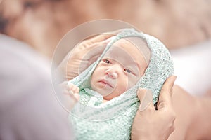 Little baby girl one week in green blanket on mother lap looking at her mother. Baby clothes changing