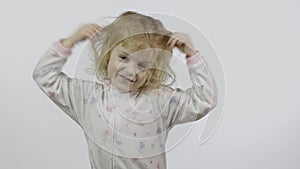 Little baby girl in pajama is fooling around and make faces. White background