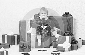 Little baby girl play near pile of gift boxes. Family holiday. Christmas gifts for toddler. Gifts for child first