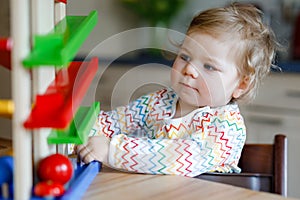 Little baby girl playing with educational toys at home or nursery. Happy healthy toddler child having fun with colorful