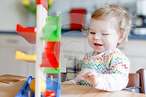 Little baby girl playing with educational toys at home or nursery. Happy healthy toddler child having fun with colorful