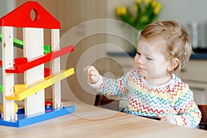 Little baby girl playing with educational toys at home or nursery. Happy healthy toddler child having fun with colorful