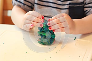 Little baby girl are playing with play dough. Mixes the colors. Girl with pink polish. Play with clay. photo