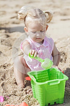 Little baby girl playing sand toys at the beach