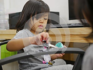 Little baby girl playing topical ointment - using a key to scoop it out and paint it on daddy`s office chair