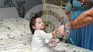 Little baby girl plays with a balloon sitting on the bed