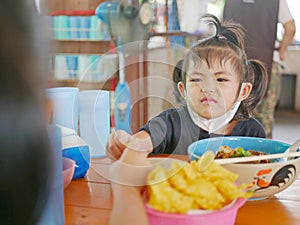 Little baby girl reaching her hand out for the same piece of deep fried wantan as taken by her older sister - sisters / siblings photo