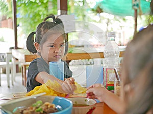 Little baby girl reaching her hand out for the same piece of deep fried wantan as taken by her younger sister - sisters / siblings photo