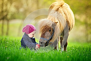 Little baby girl with red apple and pony