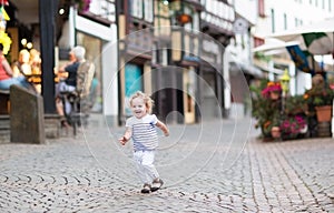 Little baby girl running in a beautiful street