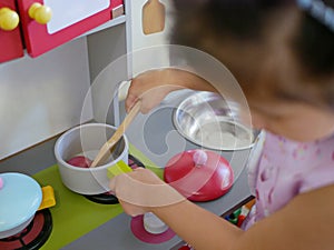 Little baby girl`s, 2 years old, hands holding on and pretend playing with kitchen toys