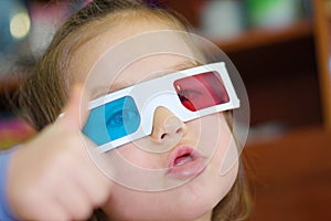 Little baby girl showing super in 3D anaglyph cinema glasses for stereo image system with polarization. 3D goggles with red and bl