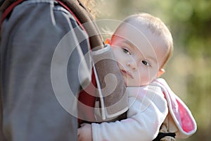 Little baby girl sitting in a baby carrier