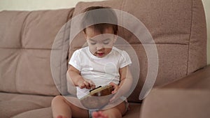 Little baby girl sitting on the couch and playing a musical instrument Kalimba