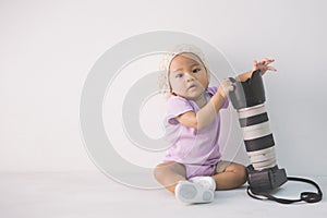 Little baby girl sitting on the floor holding dslr camera