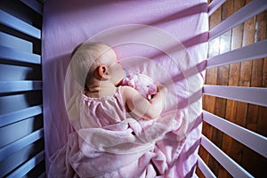 Little baby girl sleep, hug pink bear in crib bed