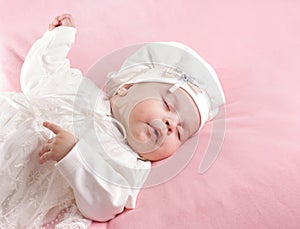 Little baby girl sleeping dressed in white suit