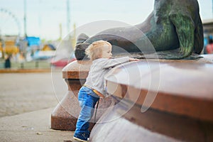 Little baby girl standing close to city fountain on a street of Helsinki, Finland