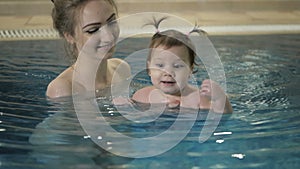 Little baby girl swimming. Learning infant child to swim