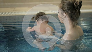 Little baby girl swimming. Learning infant child to swim