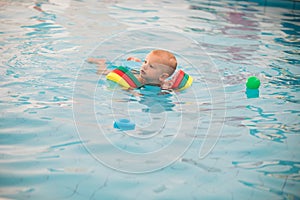 Little baby, girl swimming. Learning infant child to swim.