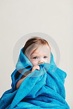 Little baby girl tucked in a cozy blue blanket.