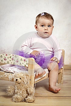 Little baby girl in tutu skirt sitting on the small bed