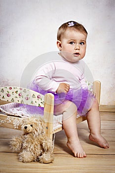 Little baby girl in tutu skirt sitting on the small bed