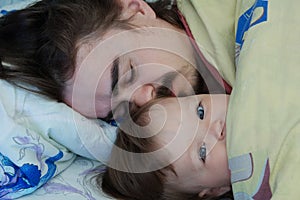 Little baby girl wake up in the morning. Parent tired sleeping. Happy Father lying on bed