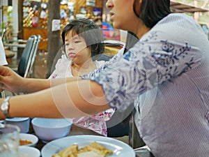 Little baby girl, 3 years old, with an unhappy face, sitting and is not eating any food - problem of a child refuses to eat at