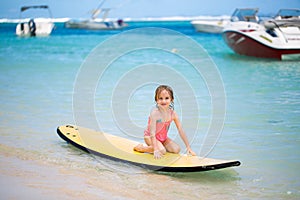 Little baby girl - young surfer with bodyboard has a fun on small ocean waves.