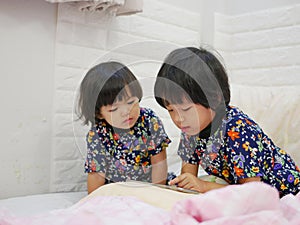 Little baby girls, sisters, 2 and 3 years old, sharing / watching a smartphone to gether - babies learning to share