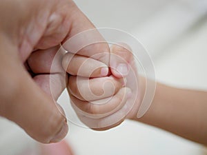 Little baby hand holding father`s finger representing father-and-child love, intimacy, and assistance